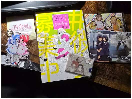 Comic Essay "Parlor" by Fujio on a pile of Yuri goods. Osaka Yuriten 2025, B. Baker.