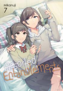 The cover of Assorted Entanglements volume 7. Shizuku and Saori lie in bed together in their school uniforms, both looking at their phones. Shizuku has her arm around Saori's shoulders and is looking over at her. You can see their matching gorilla phone charms hanging from their phone cases.