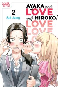 A blonde woman in pink, whispers into the ear of a woman in a grey suits and white button down shirt, who is visibly cringing with embarrassment, under the words Ayaka is in Love with Hiroko (echoed)