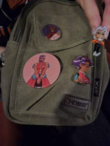Olive green canvas bag with pins and toy of Anthy and Akio from Revolutionary Girl Utena.