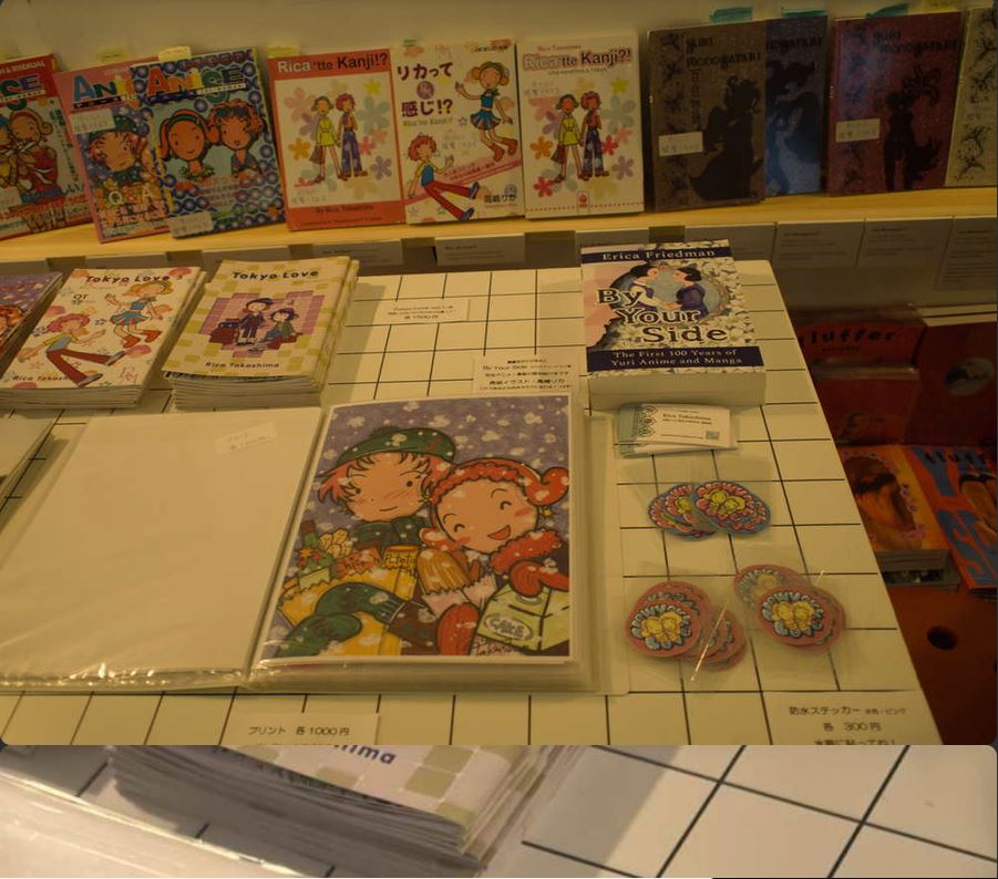 Close up on art and books for sale, original work by Rica Takashima and By Your Side.
