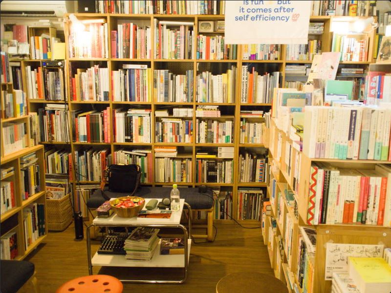 A photo of a small, cute bookstore crammed with books, and a talk event space in the middle.